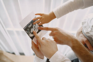 mom-dad-daughter-watching-ultrasound-picture-baby-family-light-clothes-family-expecting-baby